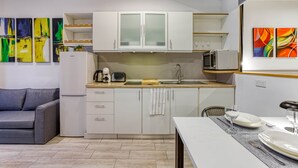 Uma cozinha moderna com armários brancos, micro-ondas, torradeira e um espaço de jantar com mesa posta para dois.