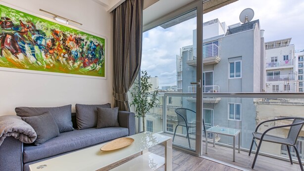 A modern living room with a grey sofa, a glass coffee table, and a large abstract painting on the wall. - St. Julian's Studio 302 - Near Beach & Paceville (Saint Julian's)