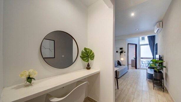 A modern living room with a white sofa, a dining table, and a large window. - St. Julian's Studio 204 - Near Beach & Paceville (Saint Julian's)