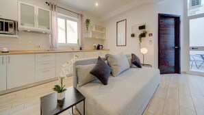 A modern kitchen with white cabinets, a microwave, and a window with curtains. - St. Julian's Studio 204 - Near Beach & Paceville (Saint Julian's)