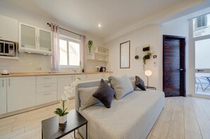 Eine moderne Küche mit weißen Schränken, einer Mikrowelle und einem Fenster mit Vorhängen.