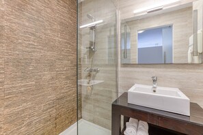 Ein modernes Badezimmer mit Duschkabine aus Glas, einem weißen Waschbecken und einem Holz-Waschtisch.