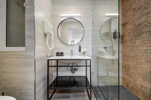 A modern bathroom with a round mirror, a sink, and a glass shower enclosure. - St. Julian's Studio 303 - Near Beach & Paceville (Saint Julian's)