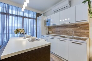 A modern kitchen with white cabinetry, a built-in microwave, and a brick backsplash. - St. Julian's Studio 303 - Near Beach & Paceville (Saint Julian's)