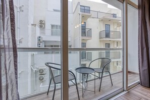 A balcony with two chairs and a table, overlooking a building with multiple balconies and air conditioning units. - St. Julian's Studio 303 - Near Beach & Paceville (Saint Julian's)