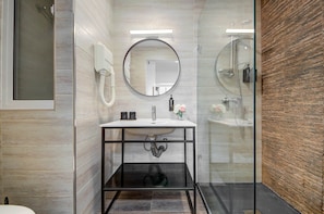 Ein modernes Badezimmer mit rundem Spiegel, Waschbecken und einer Duschkabine aus Glas.