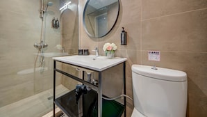 A modern bathroom with a glass shower enclosure, a round mirror, a white sink, and a toilet. - St. Julian's Studio 301 - Near Beach & Paceville (Saint Julian's)