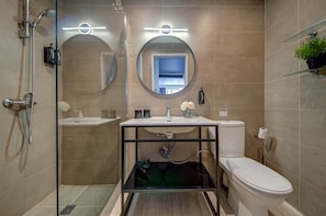 A modern bathroom with a glass shower enclosure, a round mirror, a toilet, and a sink with a mirror above it. - St. Julian's Studio 301 - Near Beach & Paceville (Saint Julian's)