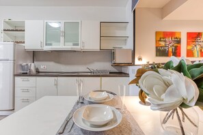 A modern kitchen with white cabinets, a granite countertop, and a dining area with a white table set for two. - St. Julian's Studio 301 - Near Beach & Paceville (Saint Julian's)