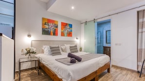 A modern bedroom with a wooden bed, a glass table, and two abstract paintings on the wall. - St. Julian's Studio 301 - Near Beach & Paceville (Saint Julian's)
