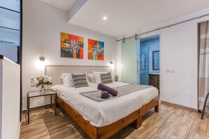 Ein modernes Schlafzimmer mit einem hölzernen Bett, einem Glastisch und zwei abstrakten Bildern an der Wand.