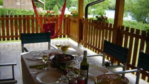 An outdoor dining area with a table set for two, featuring a bottle of wine, a bowl of food, and a basket of bread. - In quiet Vrhpolje, cozy house with 3 bedrooms. With the best view in the region. (Vrhpolje)
