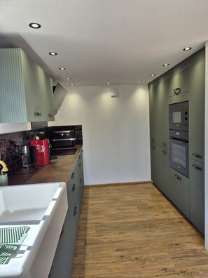 Eine moderne Küche mit integrierten Geräten, Holzboden und weißer Decke.