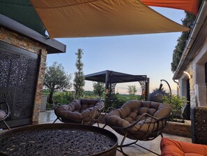 An outdoor patio with two cushioned chairs, a large metal table, and a pergola with a canopy. - THE PETITES MESANGES ESTATE (Gignac)