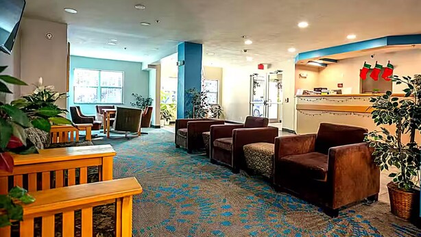 A hotel lobby with seating areas, a reception desk, and large windows.