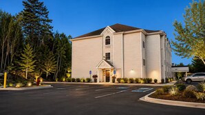 A two-story building with a flat roof, a central entrance, and a parking lot with marked spaces.