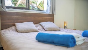 A neatly made bed with pillows and a rolled towel, a bedside lamp, and a window with a view of greenery. - Villa Anemone w/ private pool and jacuzzi in Polis (Polis Chrysochous)