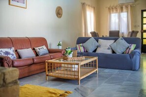 Ein Wohnzimmer mit einem braunen Ledersofa, einem blauen Sofa und einem Holztisch.