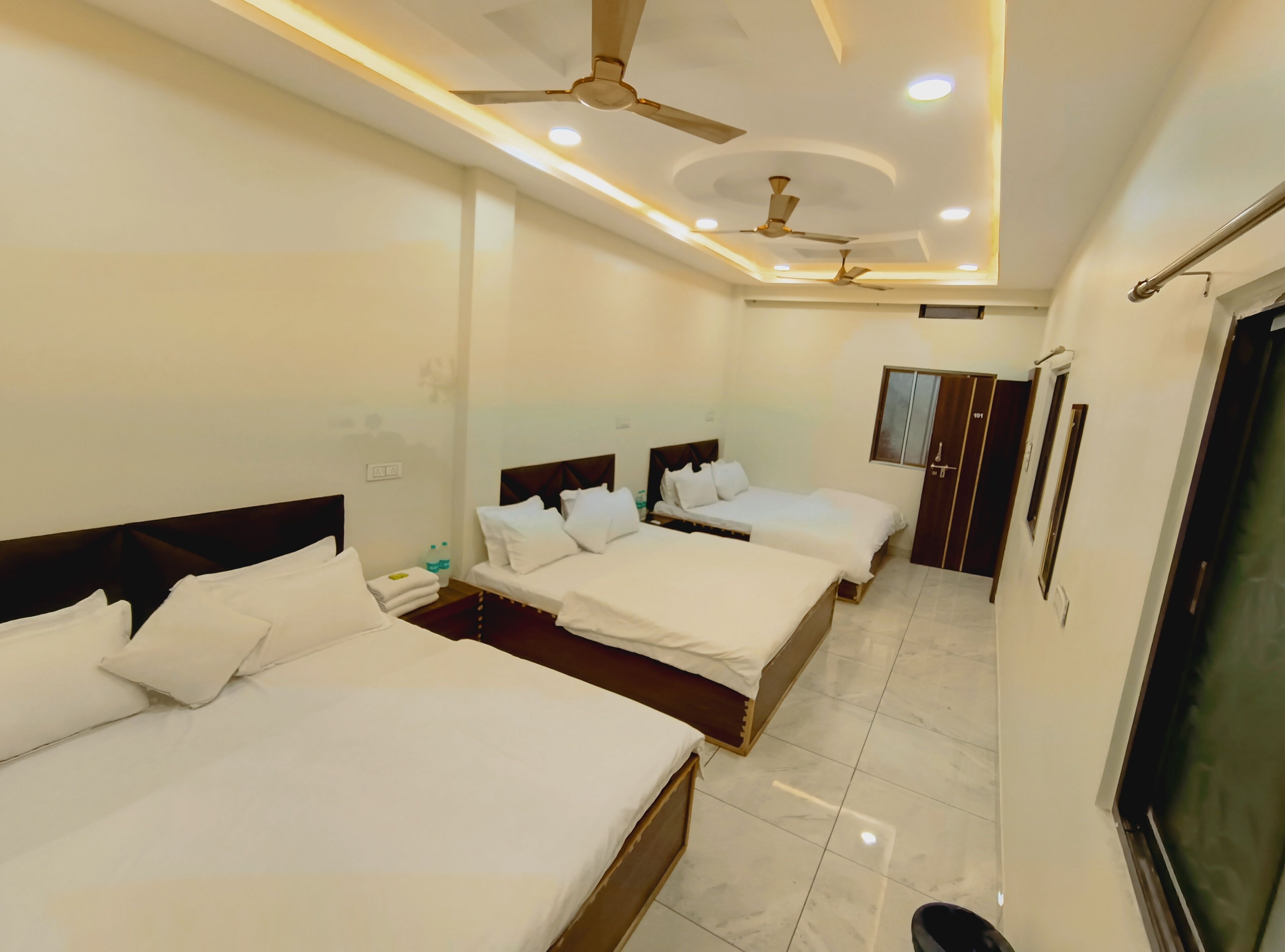 A hotel room with three beds, ceiling fans, recessed lighting, a wardrobe, and a TV.