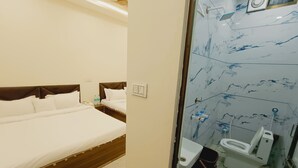 A hotel room with a bed, bedside table, and a bathroom with a toilet, sink, and shower.