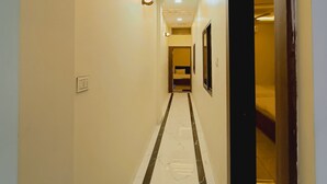 A hallway with a marble floor, recessed lighting, and a door on the right.