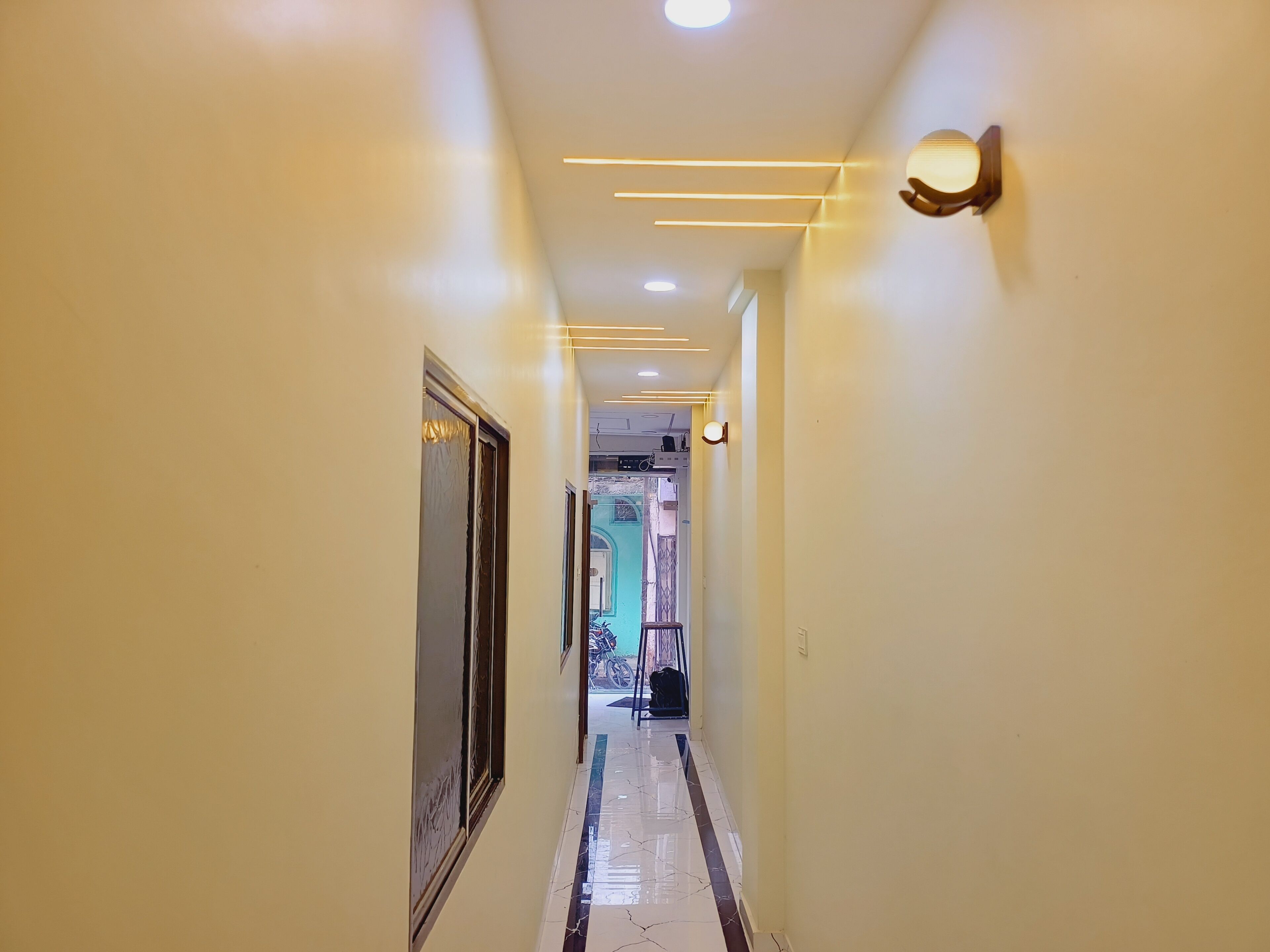 Un pasillo con suelo de baldosas, una puerta a la izquierda y un accesorio de iluminación a la derecha.