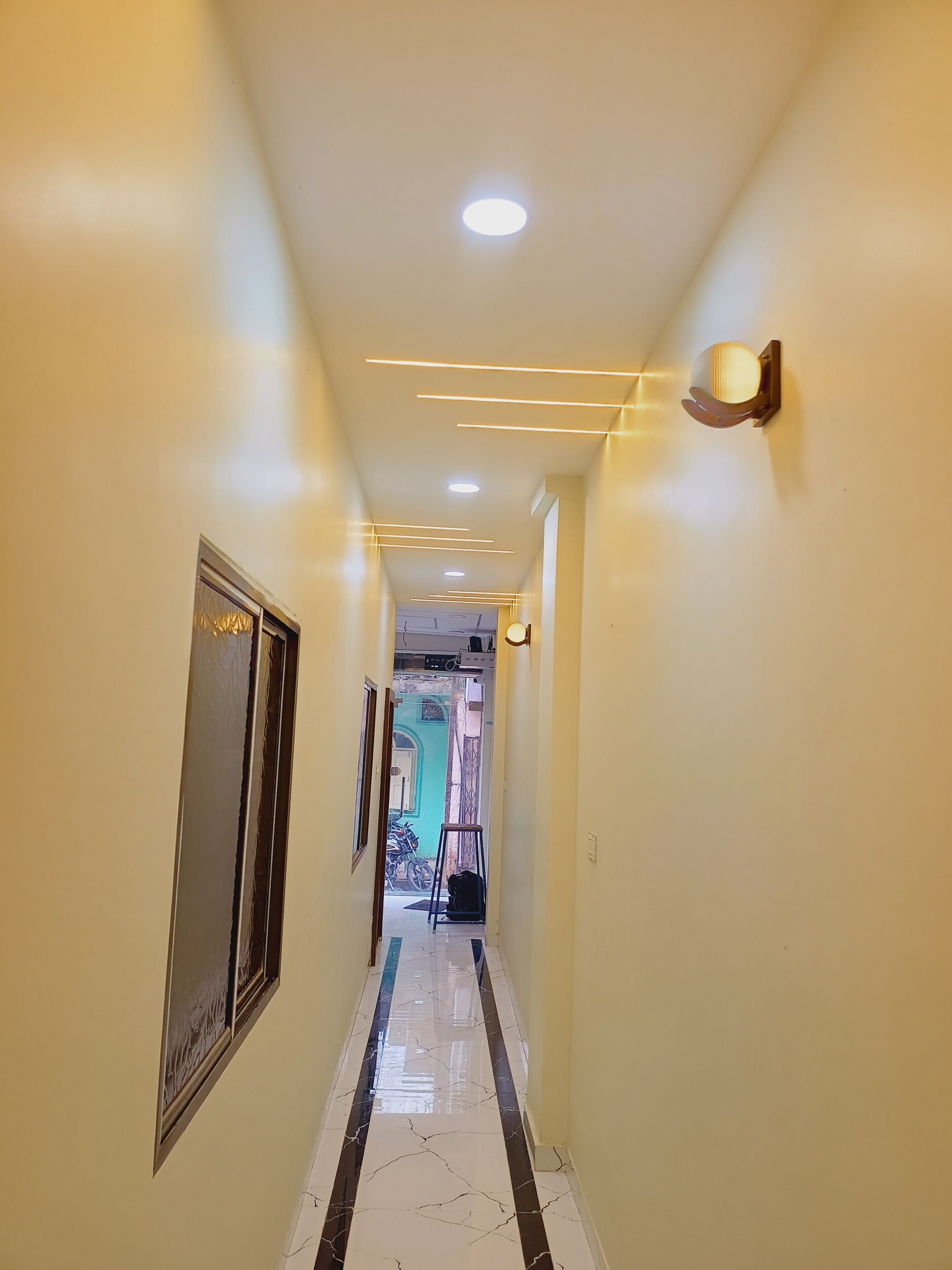 Un couloir doté d’un sol en marbre, d’un éclairage encastré et d’une porte ornée d’un panneau décoratif.
