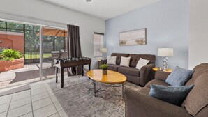 A living room with a sofa, coffee table, and a foosball table. - Sleeps 6·BBQ·Game Table·Clubhouse Amenities (Kissimmee)