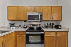 A kitchen with wooden cabinets, a microwave, a stove, and a toaster. - Sleeps 6·BBQ·Game Table·Clubhouse Amenities (Kissimmee)