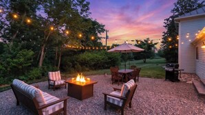 An outdoor patio with a fire pit, seating, and string lights. - Blue Ridge Getaway (Roseland)
