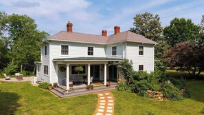 Une maison à deux étages avec un porche couvert, un chemin en pierre et une pelouse bien entretenue.