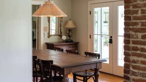 A dining area with a wooden table and chairs, a hanging lamp, a lamp on a side table, and a door with glass panels. - Blue Ridge Getaway (Roseland)