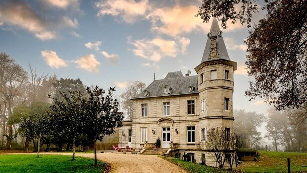 A historic building with a prominent tower, a paved driveway, and a well-maintained lawn.
