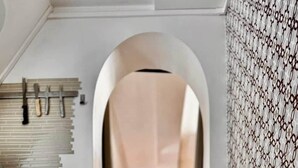 An arched doorway leading to a room with a sloped ceiling, wooden flooring, and patterned wallpaper.