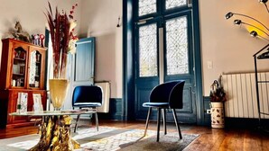A room with a wooden cabinet, a table with a vase, two chairs, a blue door, and a radiator.