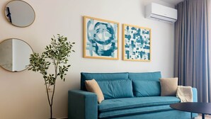 Un saló modern amb un sofà color turquesa, dos miralls penjats a la paret, obra d'art abstracta, una planta en test i un aparell d'aire condicionat.