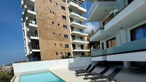 Un hotel modern amb piscina al terrat, diversos balcons i una vista despejada del mar.