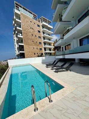 Ein modernes Hotel mit Dachpool, mehreren Balkonen und freiem Blick auf das Meer.
