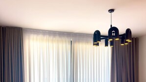 Un saló modern amb un sofà, una taula de centre rodona, una cadira i una finestra gran amb cortines.