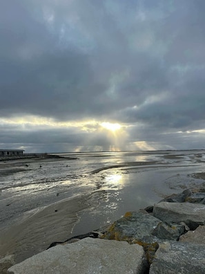 A beach with rocky foreground, a pier, and a cloudy sky. - Moon Tide - Bayside Beach Access & Parking (Provincetown)