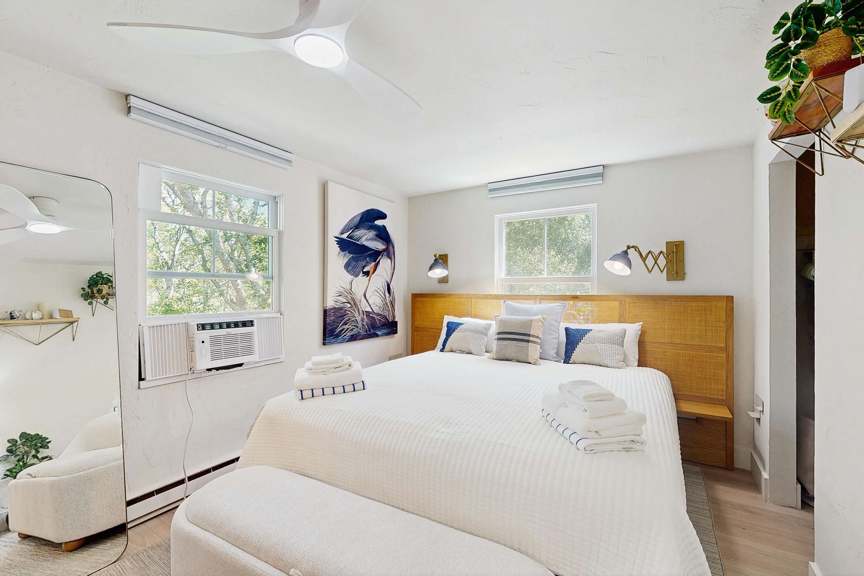 Una habitación de hotel moderna con una cama grande, mesitas de noche, una ventana y un ventilador de techo.