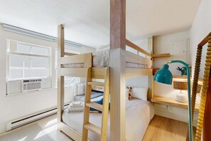 A bunk bed room with a wooden ladder, a bedside table with a lamp, and a window with blinds. - Moon Tide - Bayside Beach Access & Parking (Provincetown)