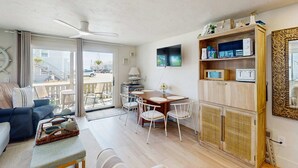 Uma sala de estar moderna com sofá, mesa de jantar, cadeiras, ventilador de teto e televisão.