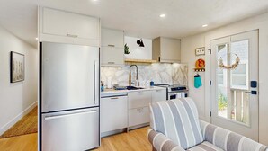 Cozinha compacta com eletrodomésticos modernos, um sofá e uma janela com vista.