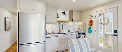 A compact kitchen with modern appliances, a sofa, and a window with a view.
