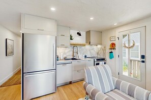 Una cocina compacta con electrodomésticos modernos, un sofá y una ventana con vistas.