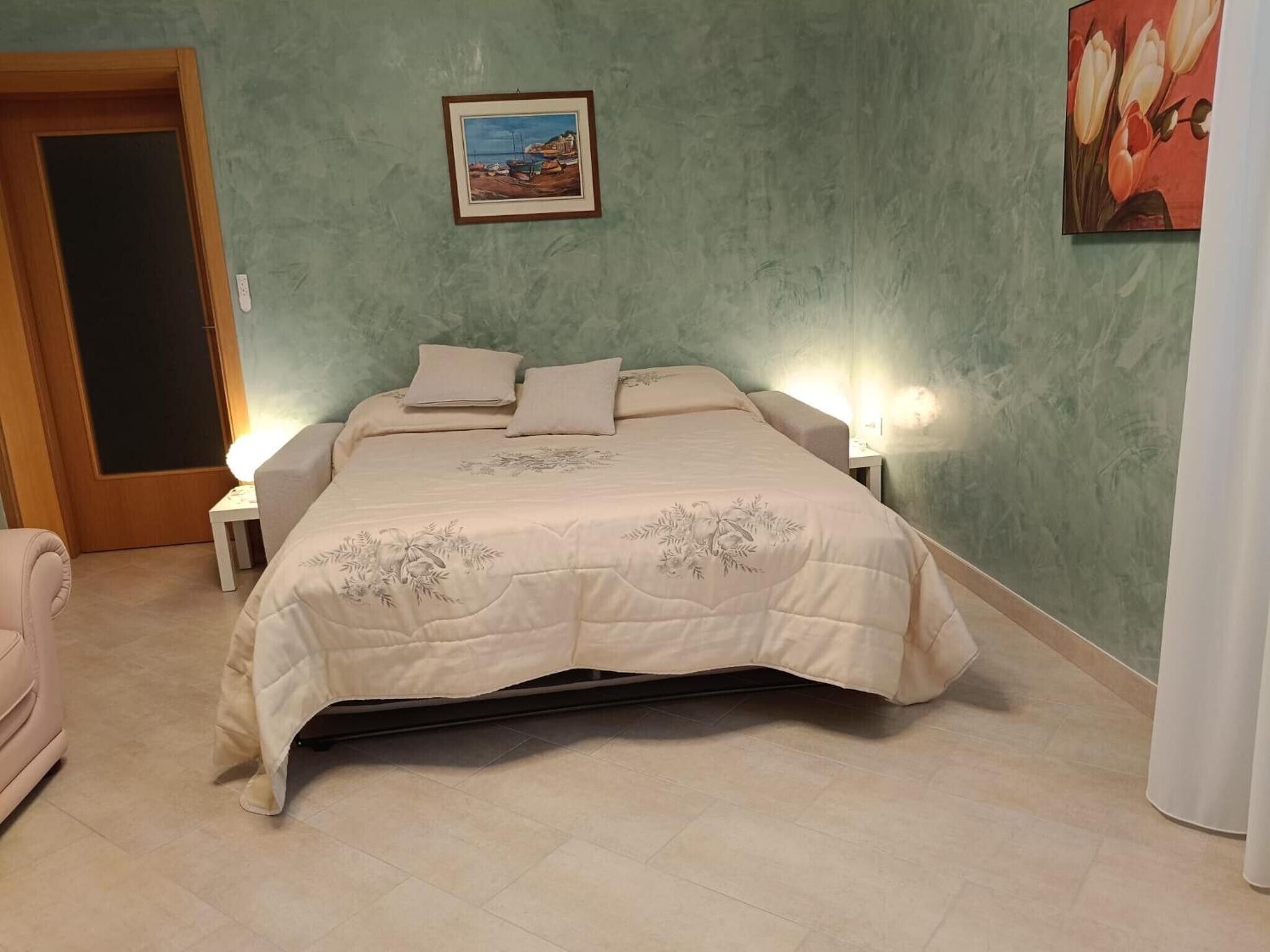 Une chambre à coucher avec un lit, des tables de chevet, une porte et un tableau au mur.