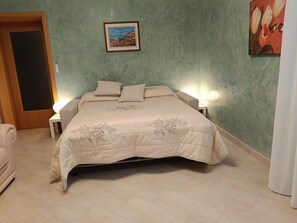 Ein Schlafzimmer mit Bett, Nachttischen, einer Tür und einem Bild an der Wand.
