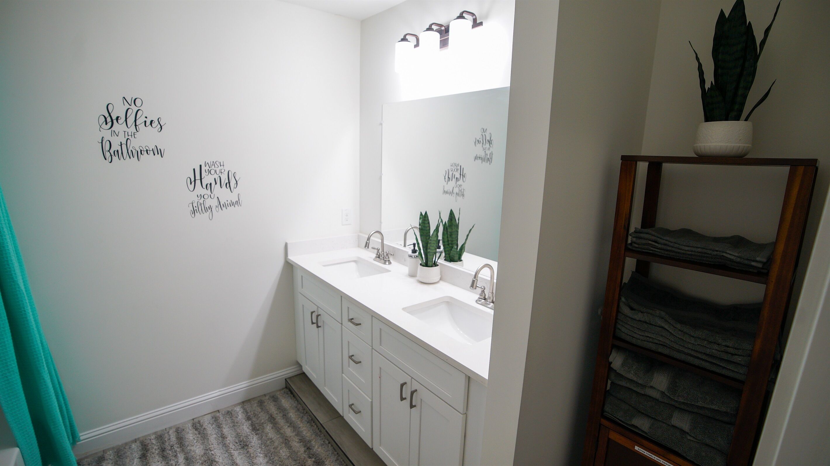 Un bagno con un lavandino bianco, due rubinetti, uno specchio e un portaservizi.