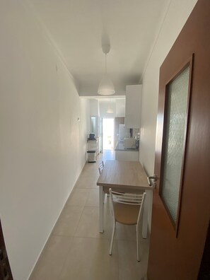 A hallway leading to a dining area with a table and chairs, a kitchen in the background, and a door with a frosted glass panel. - Holiday Home 'A Casa Da Velha' with Private Terrace, Wi-Fi and Air Conditioning (Alvor)
